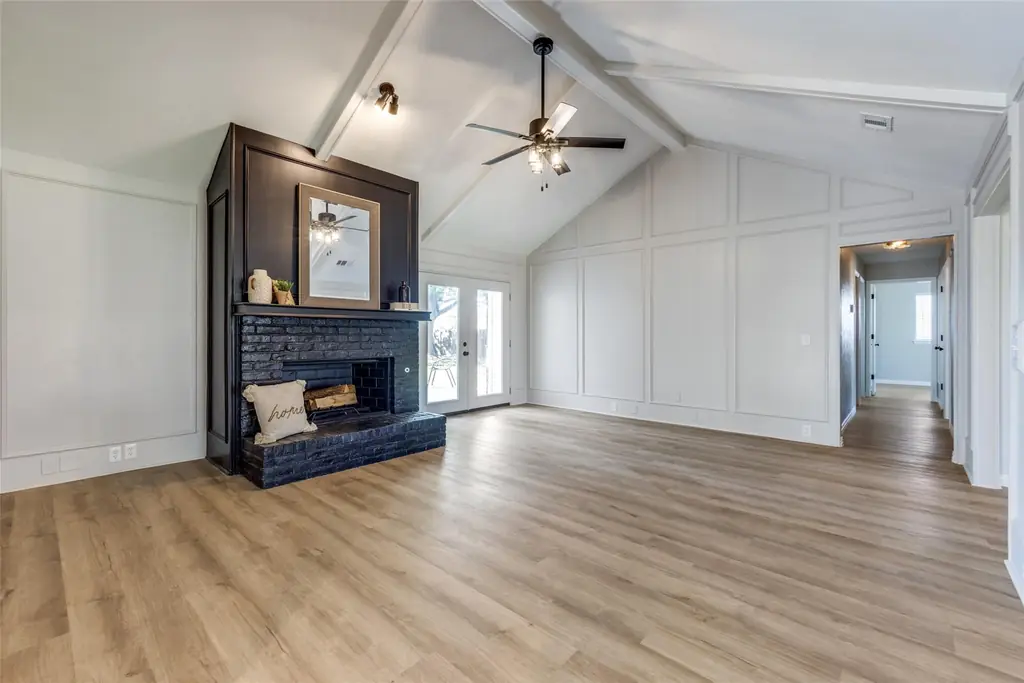 Living room finished by YourHandyman DFW with repainted walls and ceiling, a blackened brick fireplace and new plank flooring